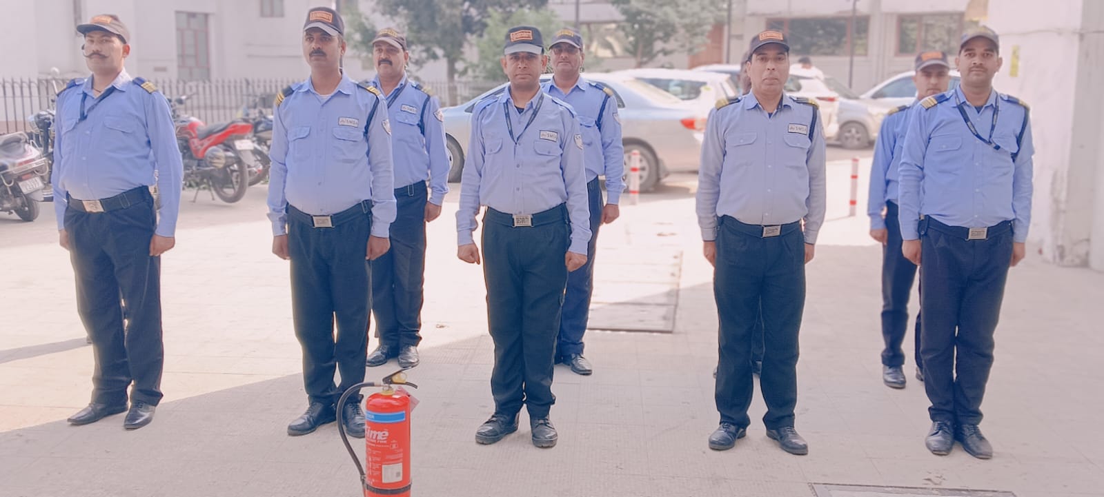 Security guards standing in formation outdoors with a fire extinguisher in the foreground